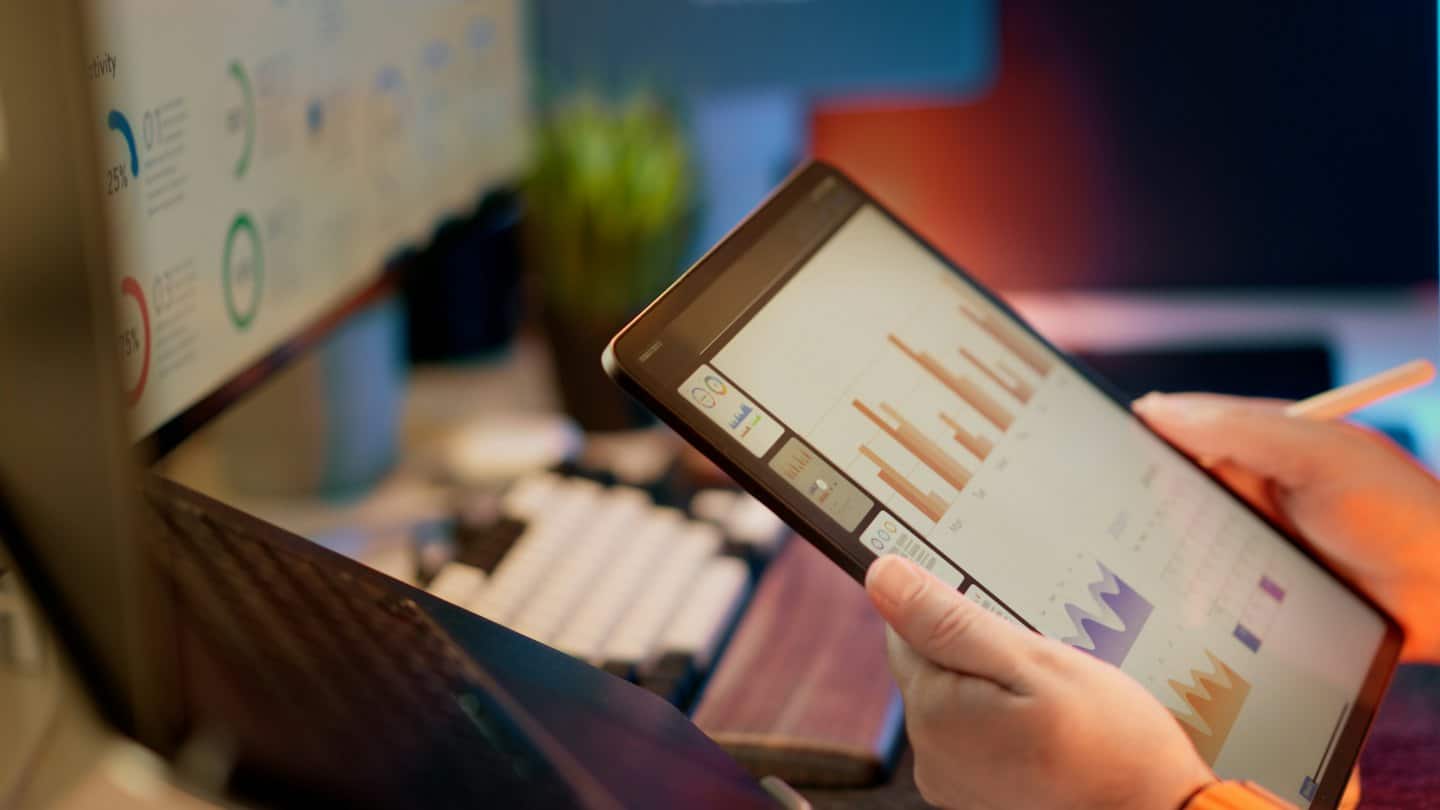 Persona che analizza grafici aziendali su un tablet alla scrivania.