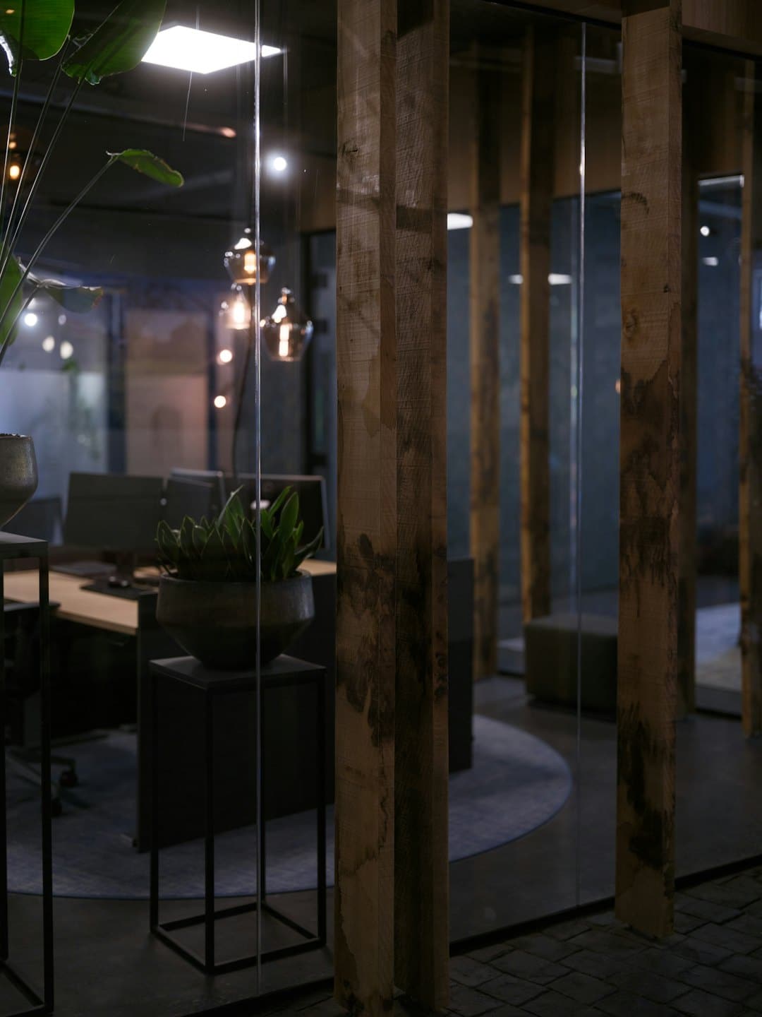 Interno di un ufficio moderno con piante e travi in legno.