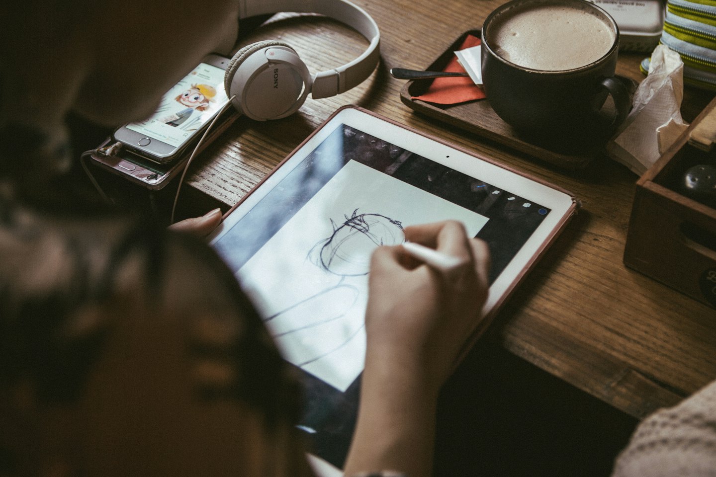 Artista che disegna su una tavoletta grafica a una scrivania di legno.